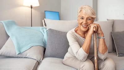 Senior woman smiling while sitting on a sofa.