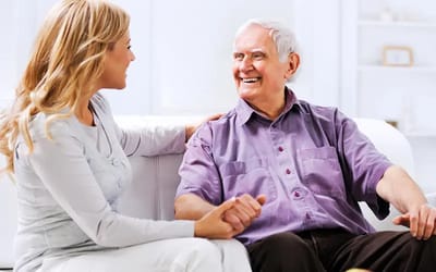 A caregiver interacts joyfully with a senior man.