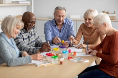 Residents engaged in an art activity at a table.
