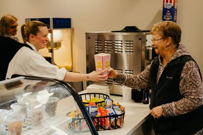 Staff serving popcorn to a resident in a dining area.