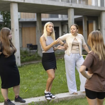 Group of four women engaged in discussion outdoors.