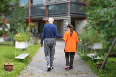 A resident walking with staff in a garden