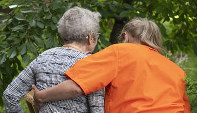 Senior resident with caregiver outdoors in a garden