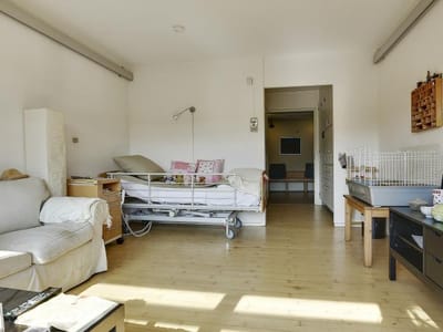 A well-lit resident room with a bed and seating area.