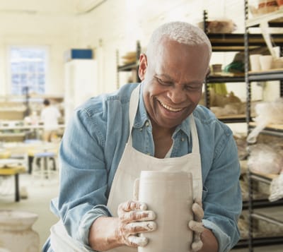 Senior man enjoying pottery class in art studio.