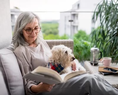Senior reading with a dog on a balcony