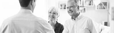 Two smiling seniors interacting with a staff member.