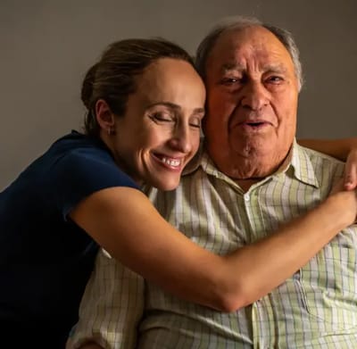 A caregiver and senior man sharing a joyful moment.