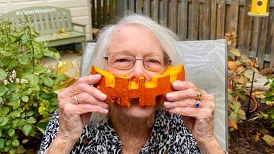Senior woman playfully holding carved pumpkin