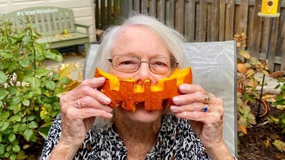Senior woman enjoying an outdoor activity with a pumpkin.