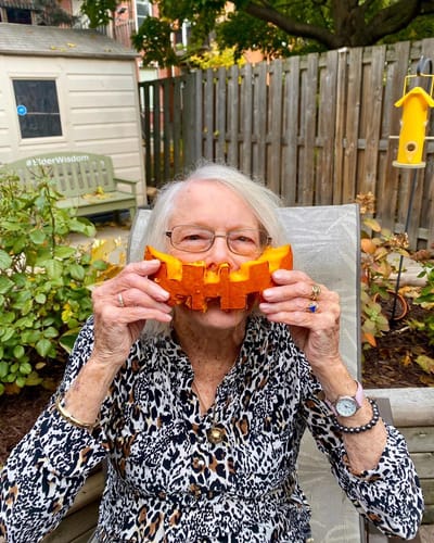 Senior woman playfully holding a pumpkin