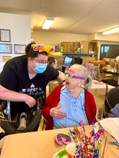 Staff member interacting with a resident at a birthday celebration.