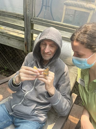 Resident enjoying time with staff outdoors.