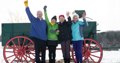 Four residents celebrating outdoors in winter attire.