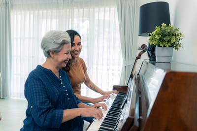 Residents playing piano together in a bright activity room