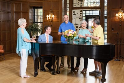 Residents and staff enjoying a gathering around a piano