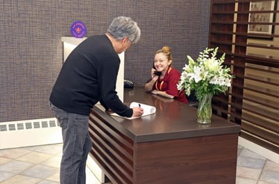 Staff member assisting a resident at the reception desk