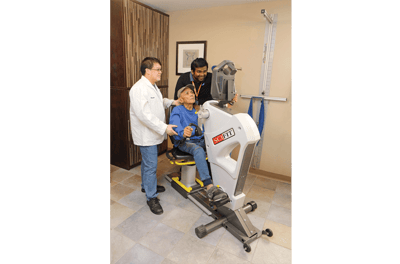 Residents using therapy equipment with staff assistance