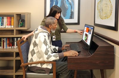 Resident and staff member using a computer in a common area
