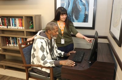 A resident using a computer with staff assistance