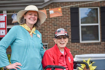 A staff member with a resident outdoors at a facility event
