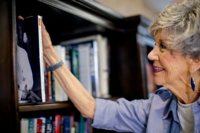 Resident reaching for a book on a shelf