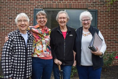 Four smiling residents posing outside