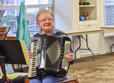 Resident playing accordion in a common area