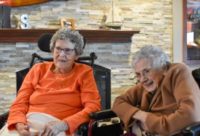Two elderly women chatting in a common area