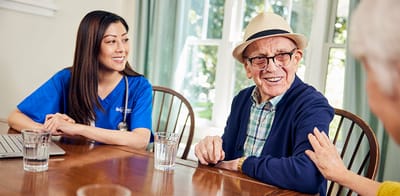 A caregiver interacting with a senior resident at a table.