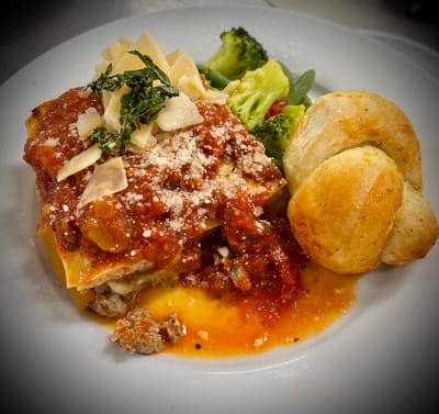 Delicious lasagna served with vegetables and bread rolls