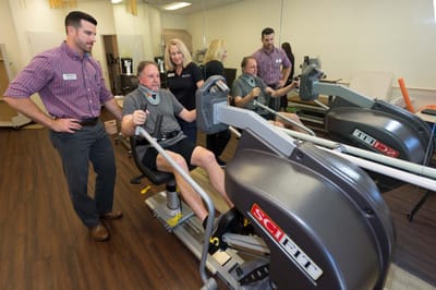 Residents engaging in fitness activities with staff assistance.