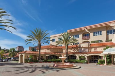 Exterior view of The Springs of Pacific Regent with palm trees.