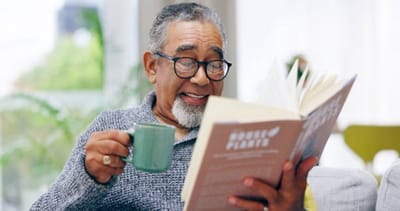 Senior man enjoying a book and tea.