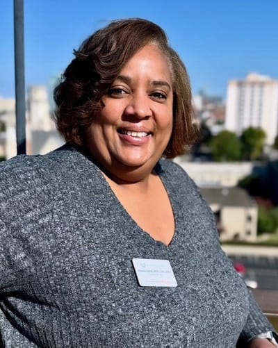 Staff member smiling outdoors with city view