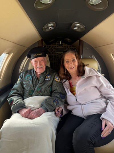 Veteran seated with companion in an aircraft