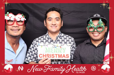 Three men wearing festive glasses and a Merry Christmas sign.