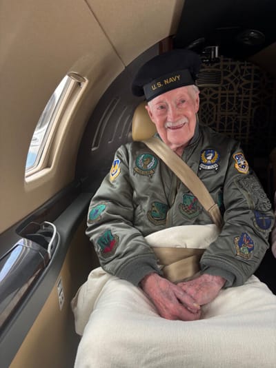 Elderly man in a U.S. Navy jacket inside a jet