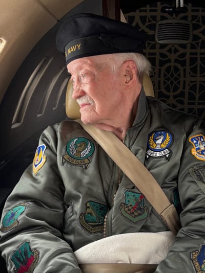 Elderly veteran wearing a Navy jacket in a vehicle