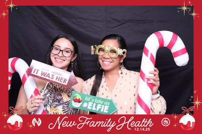 Two women posing with candy cane props at a festive event.