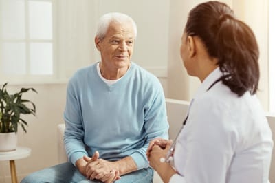 Senior man talking with healthcare professional indoors.
