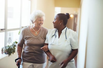 Nurse assisting elderly resident in hallway