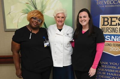 Three staff members posing together in a common area.