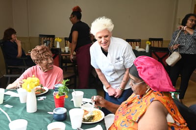 Residents enjoying a meal with staff interaction.