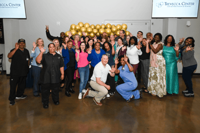 Group photo of staff and residents celebrating together.
