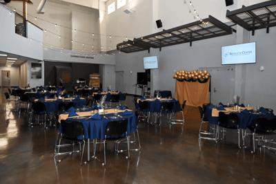 Dining setup in an event space with tables and decorations.
