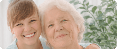 Smiling woman with elderly woman, embracing each other