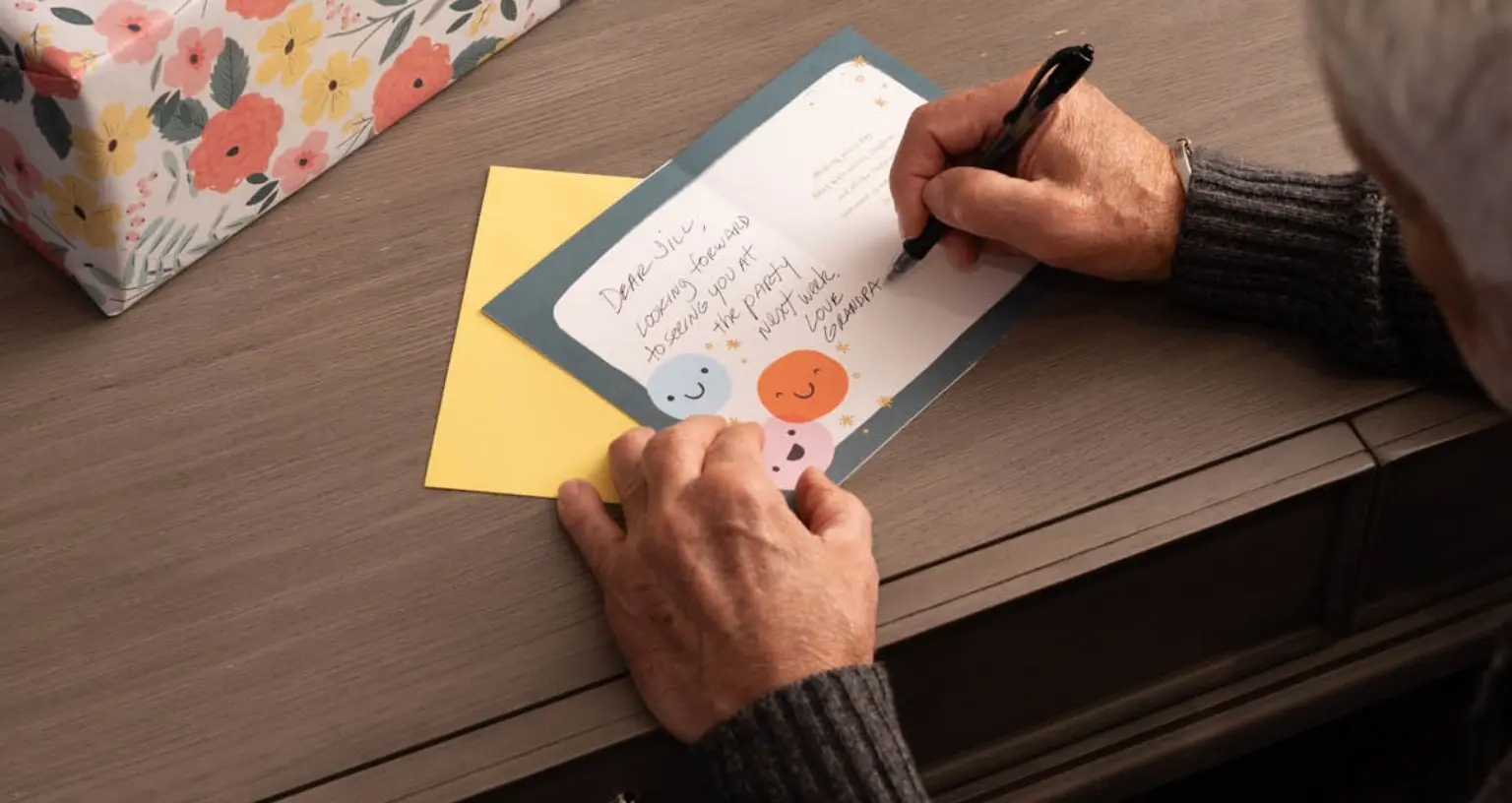 Resident writing a card with smiles illustration.