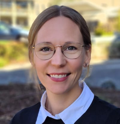 Woman smiling outdoors near facility entrance.