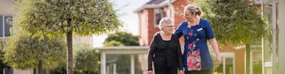 Caregiver and resident walking in outdoor garden